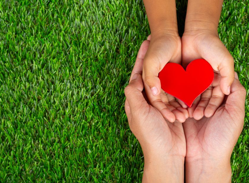 red heart shape in family member's hands holding