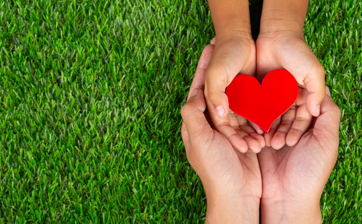 red heart shape in family member's hands holding